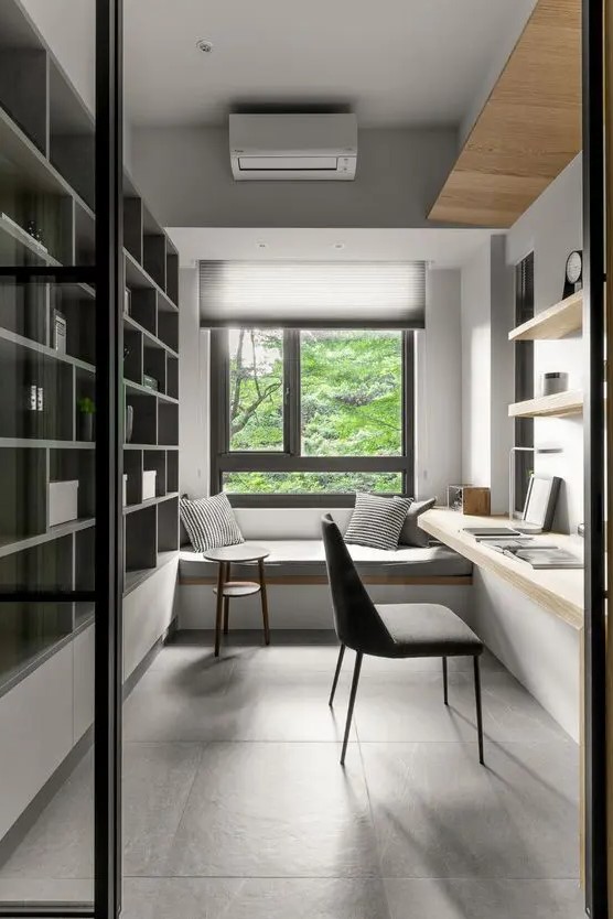 a minimalist home office with a built-in storage unit, a built-in desk and shelves, a windowsill daybed and pillows