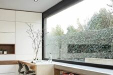 a minimalist home office with a panoramic window, a white sleek storage unit, a windowsill daybed and a built-in desk