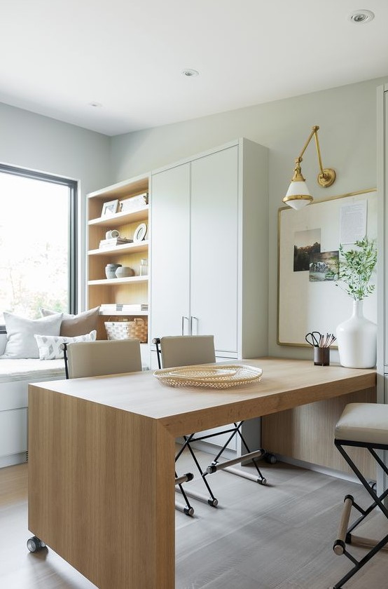 a neutral organic home office in dove grey, with a large wooden desk, a cupboard and a storage unit and a window daybed