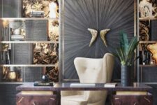 a sophisticated home office with a gold and black wall, shelves, a dark desk and a large wingback chair, a gold pendant lamp