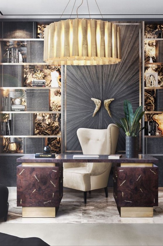 a sophisticated home office with a gold and black wall, shelves, a dark desk and a large wingback chair, a gold pendant lamp