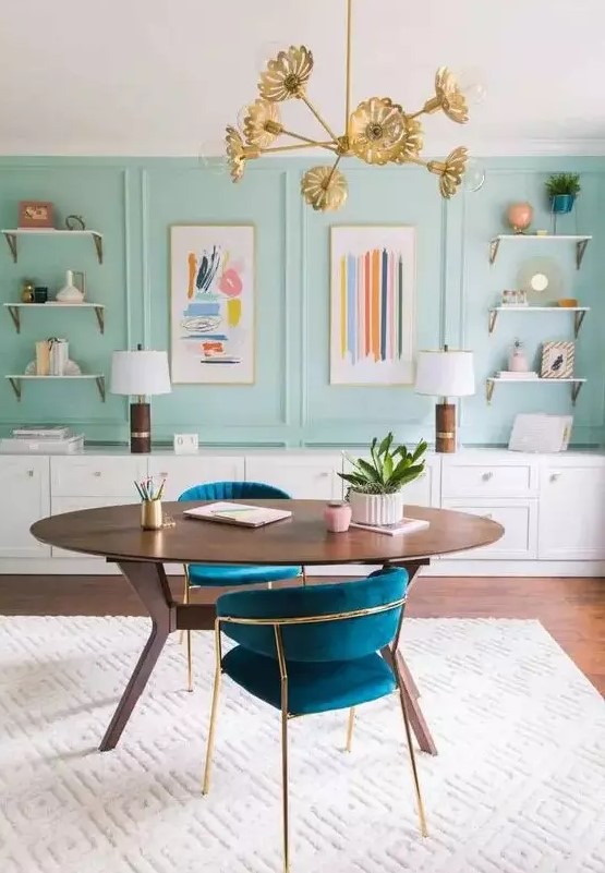a sophisticated home office with aqua panels, open shelves, a long storage unit, an oval desk and lovely navy chairs