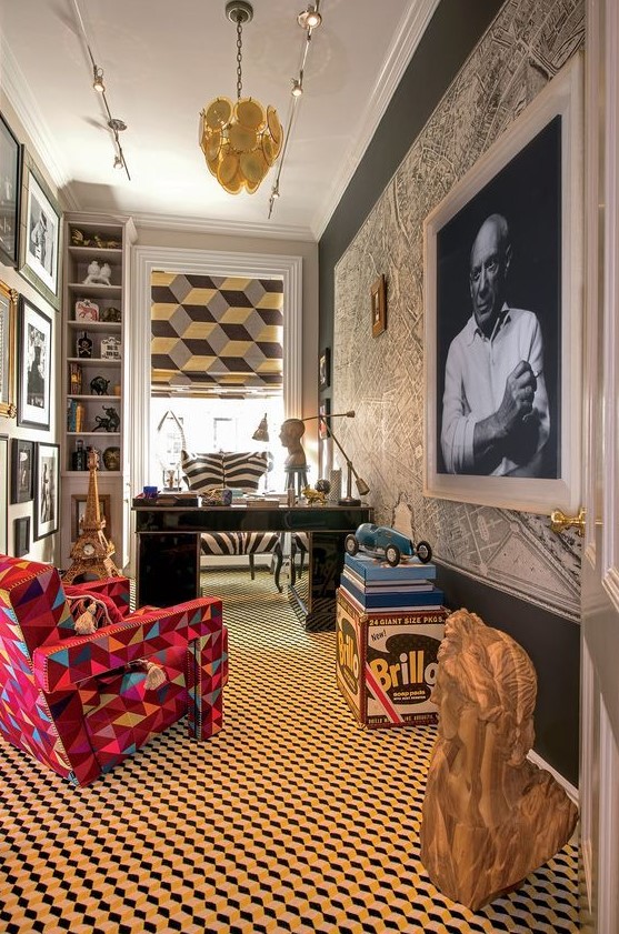 a vibrant maximalist home office with a map and a bold artwork on the wall, a gallery wall, a geometric floor and a printed curtain