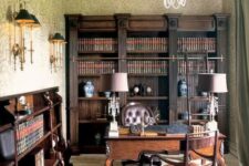 a vintage home office with dark-stained bookcases and bookshelves, a dark-stained desk and leather chairs, table and wall lamps and a cool chandelier