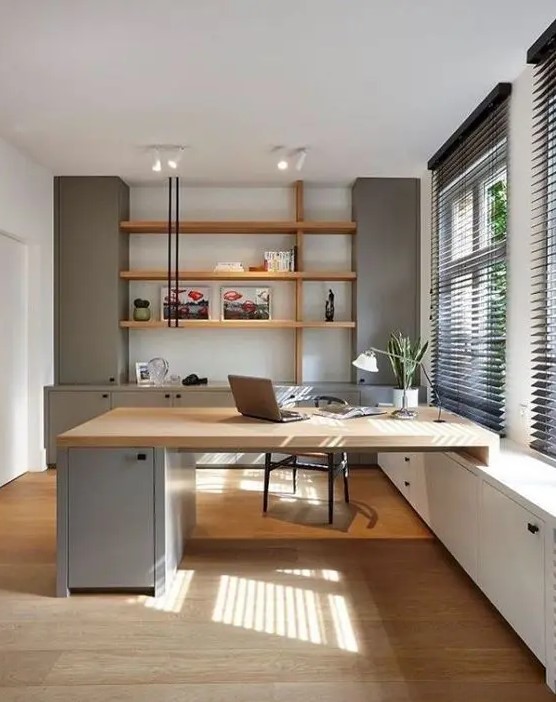 a welcoming contemporary home office with light grey storage units, stained shelves, a built-in matching desk and a black chair