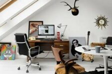 an eclectic attic home office with large skylights, a stained desk and a black leather chair, a round table and a wooden chair, a cool rug and some artworks