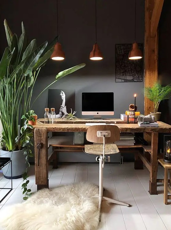 an eclectic home office with grey walls, a rustic wooden desk and beams, an industrial stool and pendant lamps