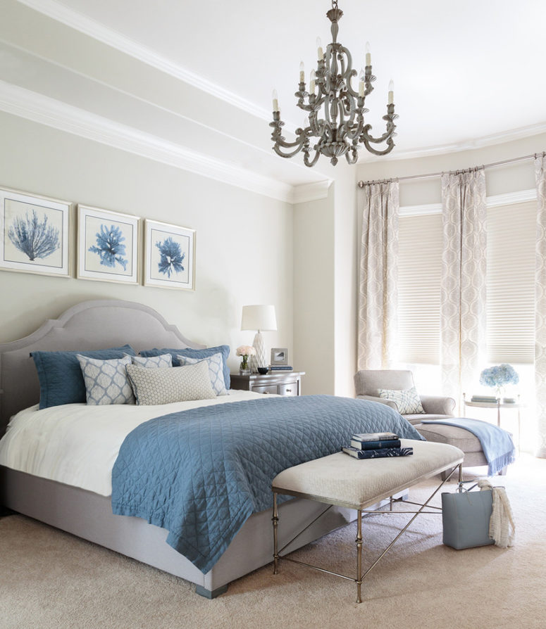 a sea-inspired bedroom with a grey floor, walls, curtains and an upholstered bed plus blue textiles and artworks