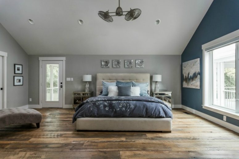 an attic bedroom done in dove grey with a statement blue wall and blue bedding