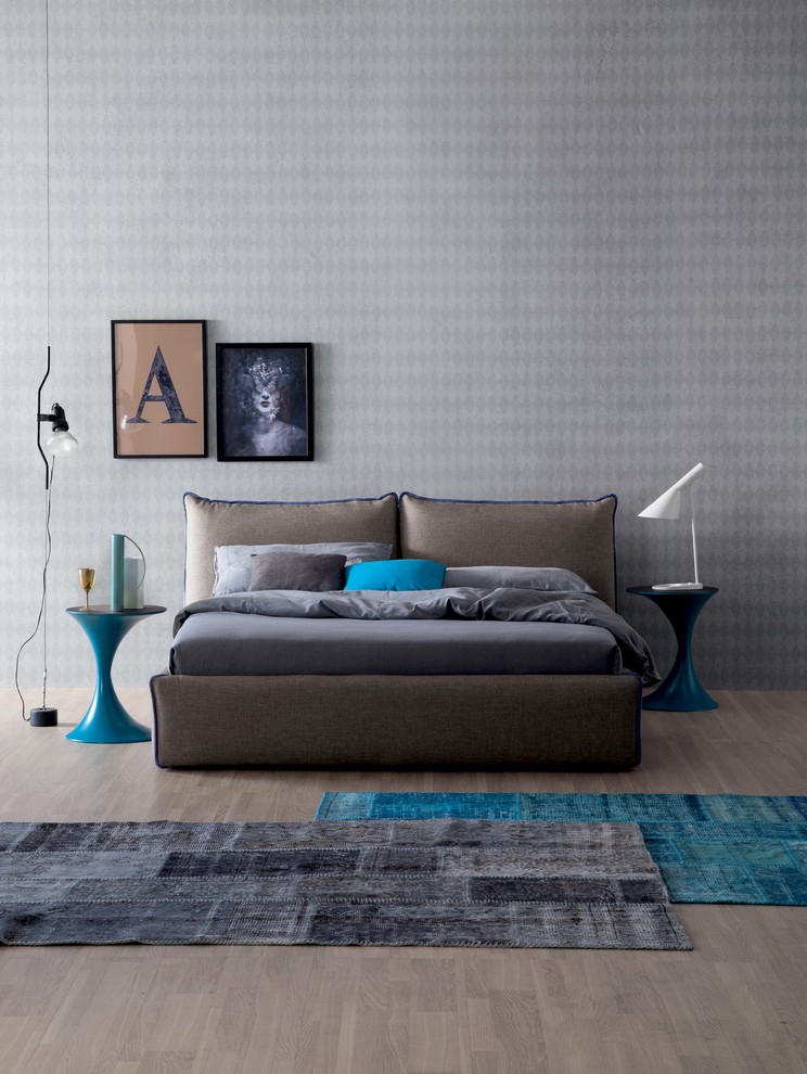 a bold contemporary bedroom with grey wallpaper walls, an upholstered bed, grey and turquoise rugs and turquoise accents here and there