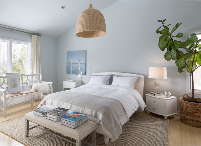 a creamy, dove grey and light blue bedroom with a wicker lampshade, some grey textiles and creamy furniture