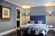 a contemporary bedroom with grey walls and furniture and a stunning upholstered navy bed plus grey pillows and a blanket