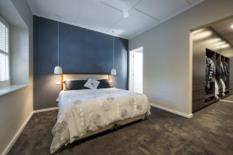 a contemporary bedroom with dove grey walls and a graphite grey carpet floor, with a navy statement wall and a grey bed