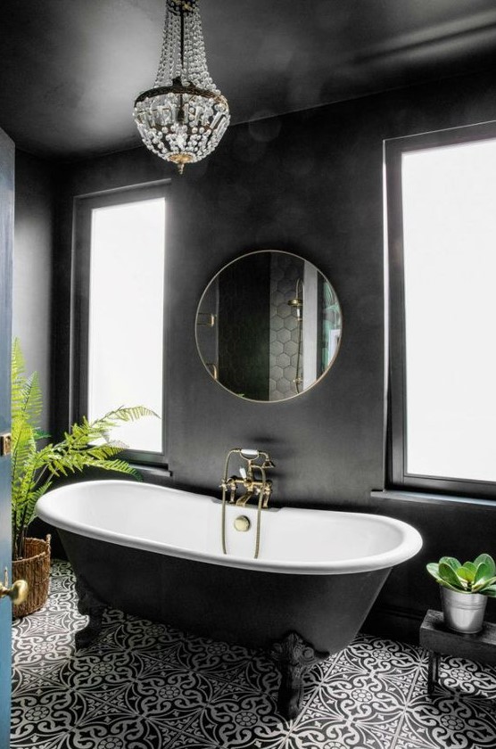 a black bathroom with painted walls, a refined black clawfoot tub, a mosaic tile floor and a crystal chandelier
