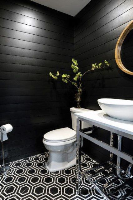 a black farmhouse bathroom with planked walls, a black and white hex tile floor, a vanity, white appliances and a round mirror