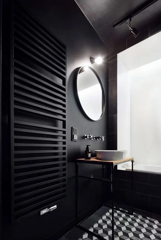 a black wall with a black radiator and black tiles on another wall, mosaic geometric tiles on the floor