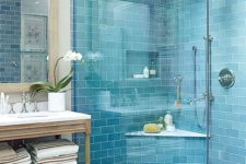 a bold blue tile shower space paired with a grey marbled tile floor and a vintage wooden vanity