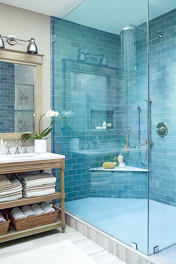 a bold blue tile shower space paired with a grey marbled tile floor and a vintage wooden vanity