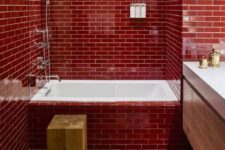 a bold red bathroom fully clad with tiles and accented with white grout plus touches of wood and white