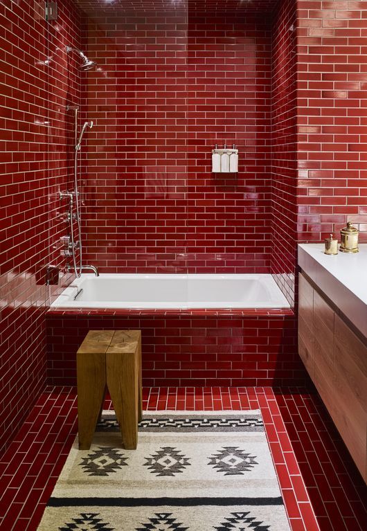 a bold red bathroom fully clad with tiles and accented with white grout plus touches of wood and white