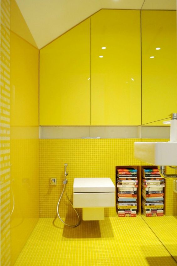 a bold yellow powder room clad with small scale yellow tiles, with bright glossy yellow cabinets and a mirror wall is a chic spot