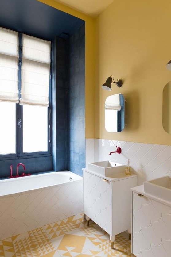 a bright bathroom with a yellow wall and a yellow and white tile floor, a blue bathtub zone and white tiles