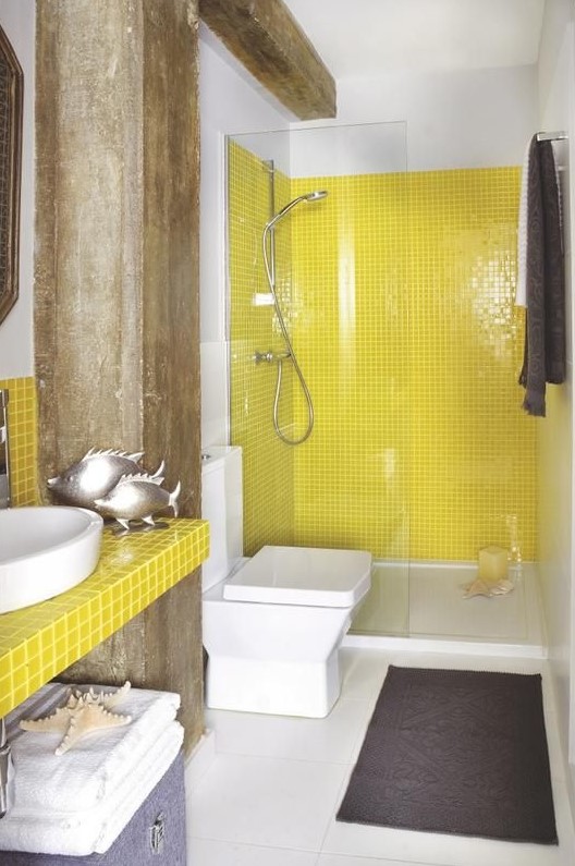 a bright bathroom with yellow tiles in the shower and a bright tile vanity, white large scale tiles and industrial wooden beams