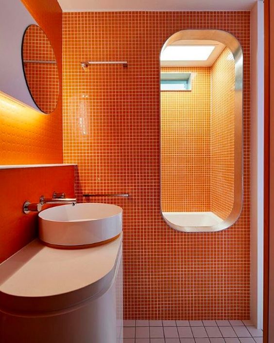 a bright modern bathroom with orange tiles on walls and a neutral floor, it's a chic and bold idea