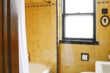 a bright vintage bathroom with yellow tiles, black touches for drama and white vintage appliances