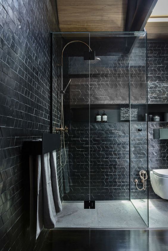 a catchy modern black bathroom with geo clad tiles, a niche shelf and a shower enclosed in glass is cool