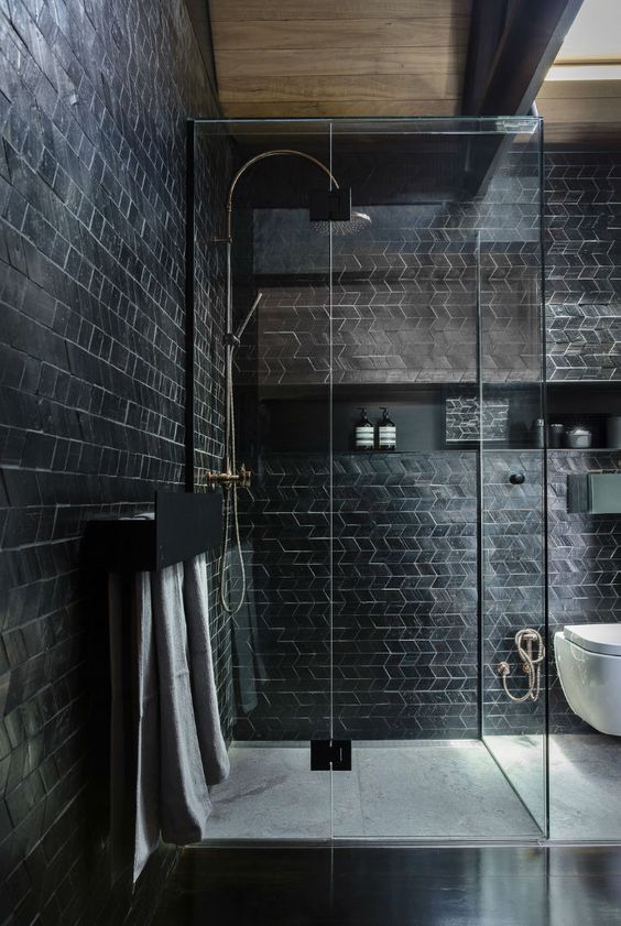 حمامات باللون الاسود A-catchy-modern-black-bathroom-with-geo-clad-tiles-a-niche-shelf-and-a-shower-enclosed-in-glass-is-cool