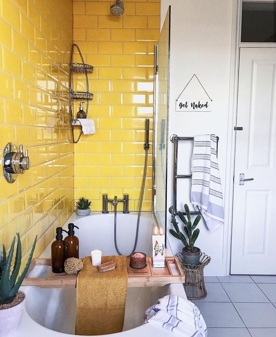 a catchy neutral bathroom with a grey tile floor and a sunny yellow tile backsplash around the bathtub