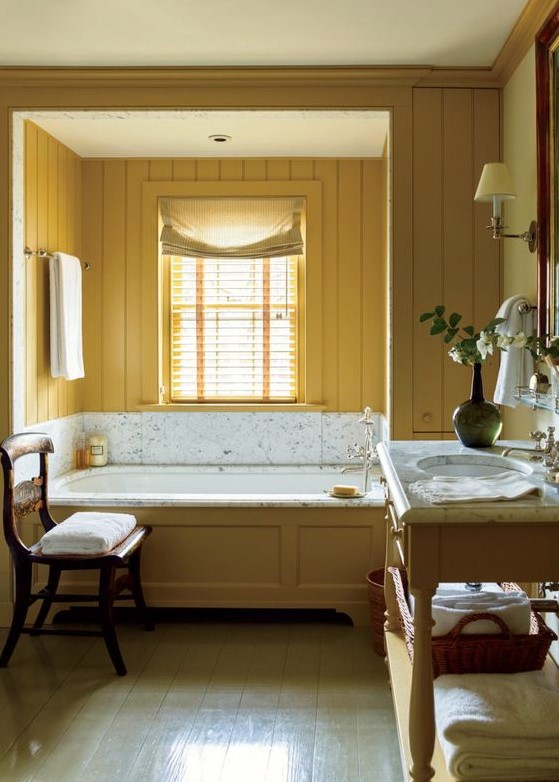 a charming vintage bathroom with mustard beadboard walls, a vanity and a bathtub clad with mustard wood and neutrals