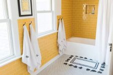 a chic bathroom with sunny yellow walls, penny tiles on the floor, black and white textiles and woven shades on the windows