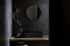 a chic minimalist black bathroom with a matte black sink and walls plus some light-stained touches