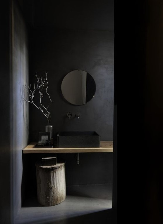 a chic minimalist black bathroom with a matte black sink and walls plus some light-stained touches