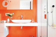 a contemporary bathroom with an orange statement wall, a matching trash can and some hardware plus refreshing whites