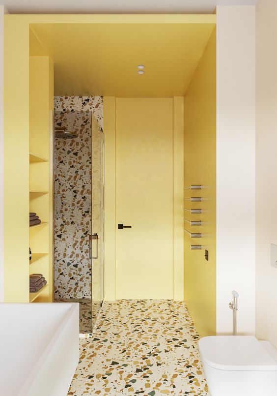 a contemporary bathroom with light yellow walls and shelves, a terrazzo floro and an accent wall in the shower and white appliances