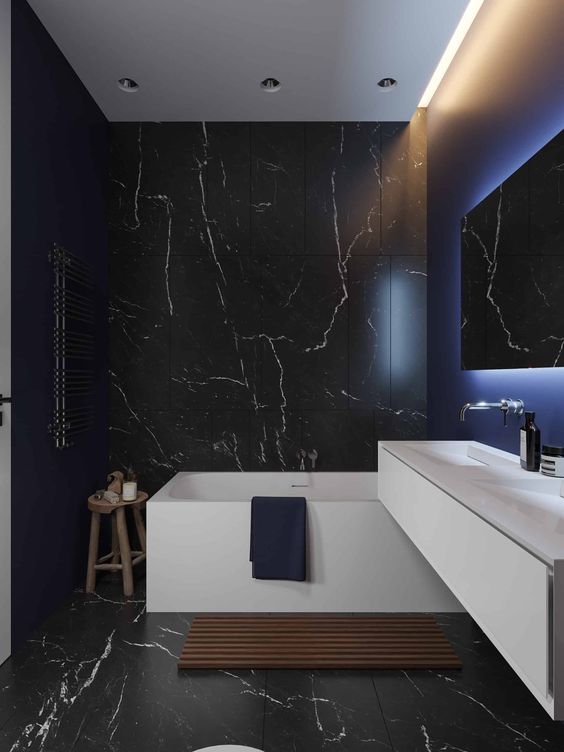 a contemporary black bathroom with black marble tiles, a white vanity and white appliances, built in lights