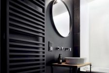 a contemporary black bathroom with matte black walls and a radiator, black tiles and a graphic tile floor