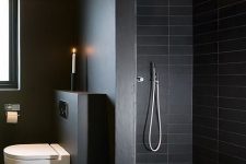a contemporary black bathroom with skinny tiles and matte walls, white applainces and stainless steel fixtures is amazing