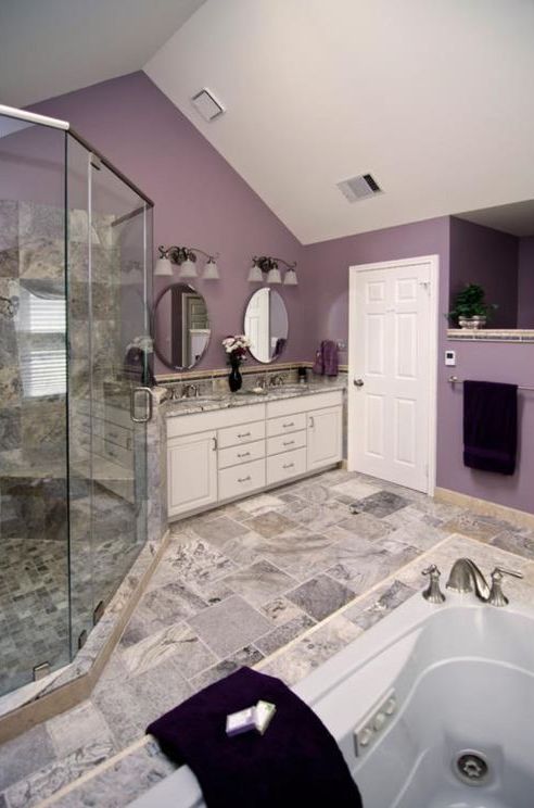 a cozy purple bathroom with stone inspired tiles and countertops, whites and chic wall lamps