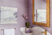 a delicate lavender and gold bathroom with a floating marble vanity and an abstract artwork