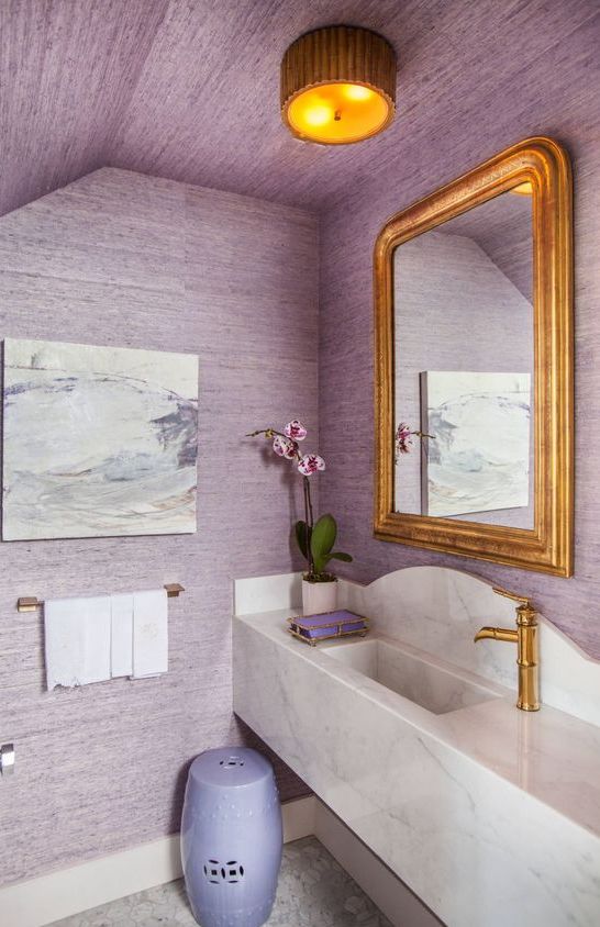 a delicate lavender and gold bathroom with a floating marble vanity and an abstract artwork