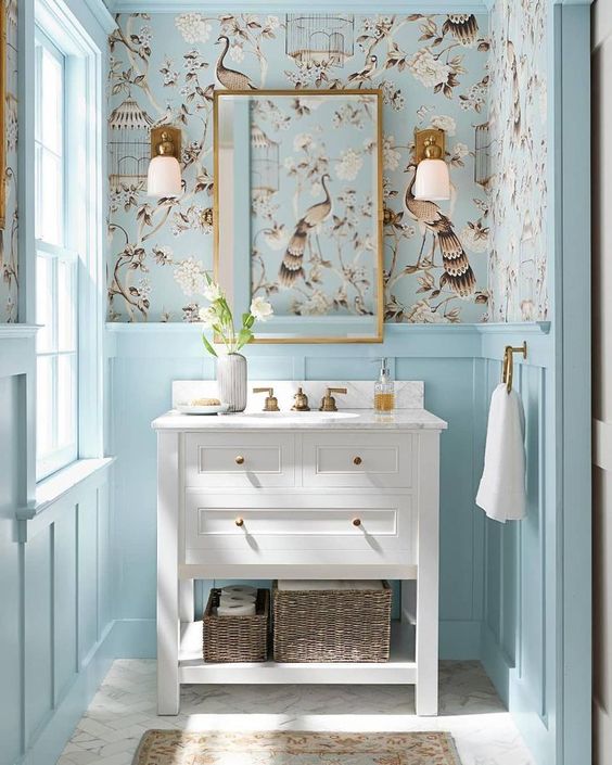 a light blue powder room done with pretty printed wallpaper and a rustic white vanity