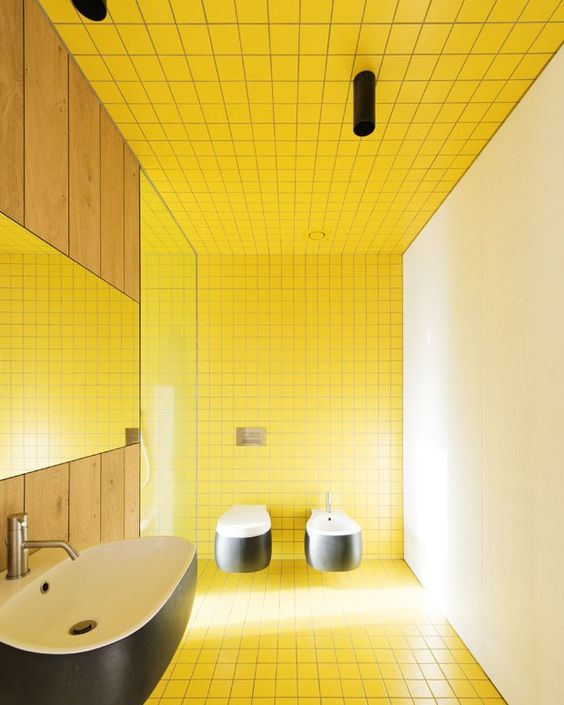 a minimalist bathroom with yellow square tiles and a neutral wlal, black and white floating appliances and black lights plus a shower with a window