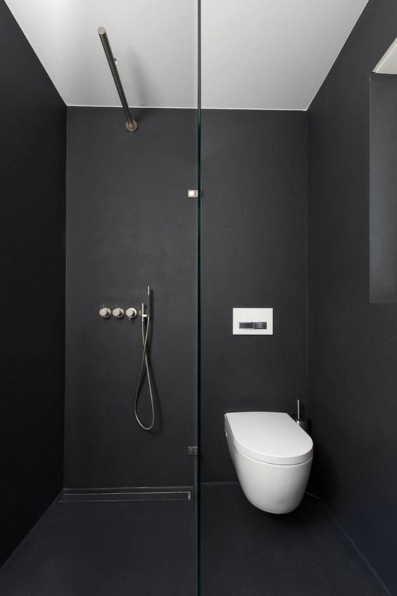 a minimalist black bathroom with matte walls and a floor, a white toilet and neutral fixtures is very laconic and simple