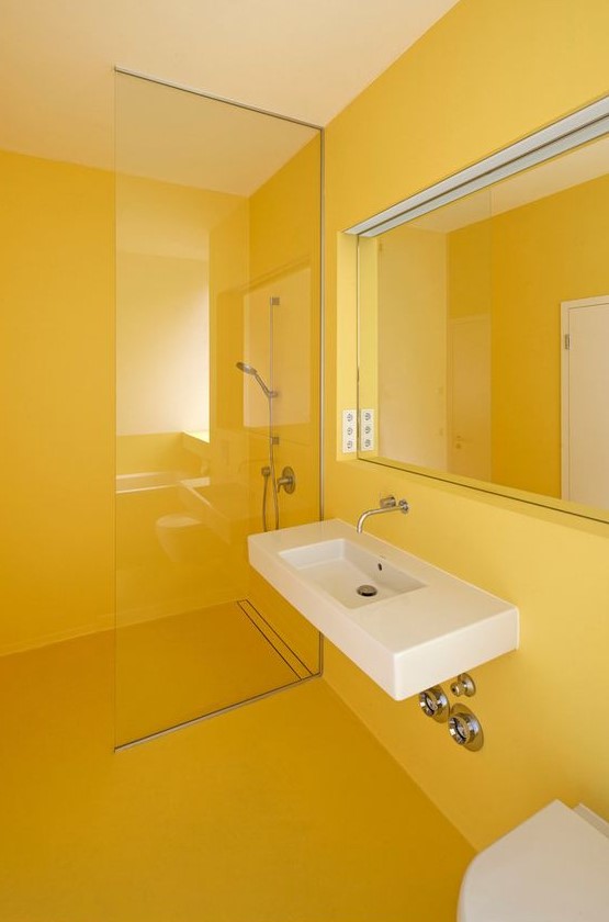 a minimalist sunny yellow bathroom done sleek and plain, with a statement mirror and a floating sink