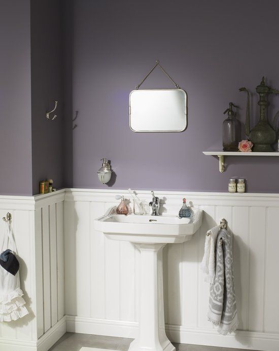 a moody modern farmhouse bathroom with purple walls, white paneling, a free-standing sink and vintage shelves