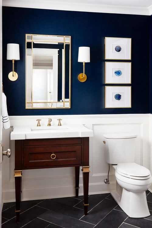 a navy statement wall and white paneling create a very elegant look and a vintage vanity adds to it